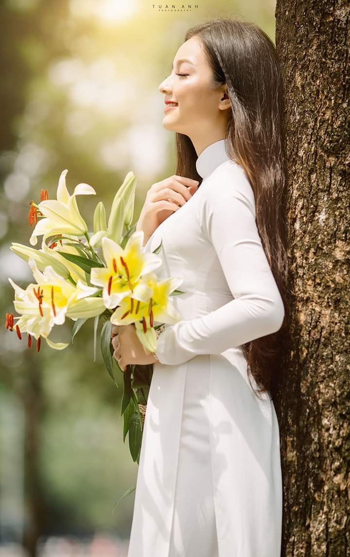 Tạo dáng chụp nghiên khi có điểm tựa Áo dài và hoa loa kèn