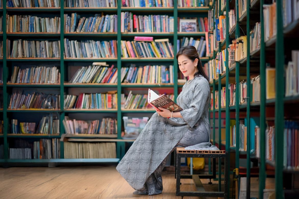 Chị gái ngồi đọc sách trong trang phục áo dài Việt Nam